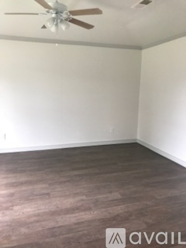 A room with a ceiling fan and wooden flooring.