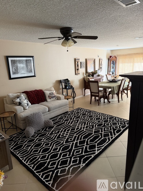 A living room with a grey couch and a black and white rug.