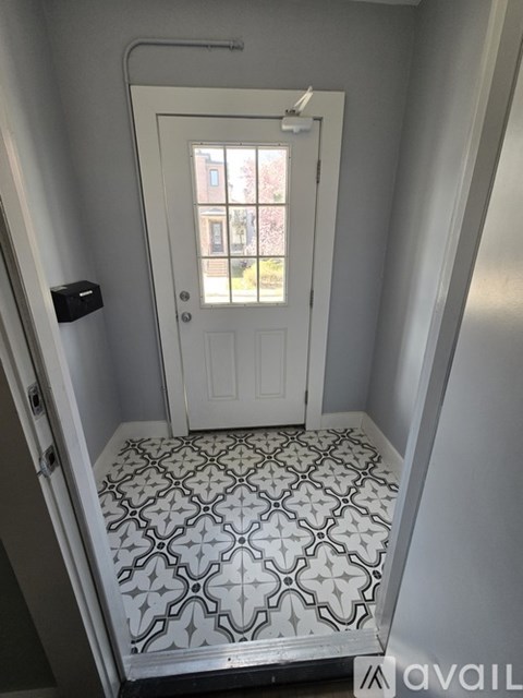 A white door with a window in the middle of a room with a tiled floor.