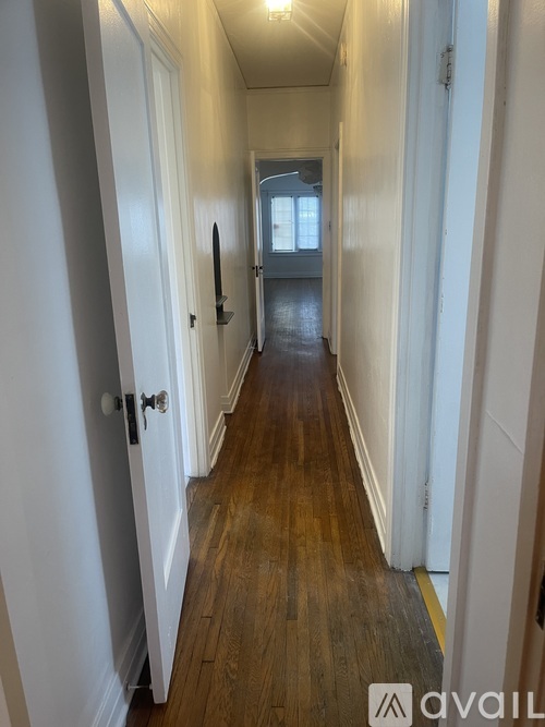 A long hallway with white doors and wood floors.