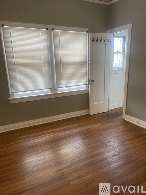 A room with wooden floors and a window with blinds.