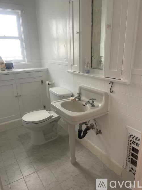 A white bathroom with a toilet, sink, and mirror.