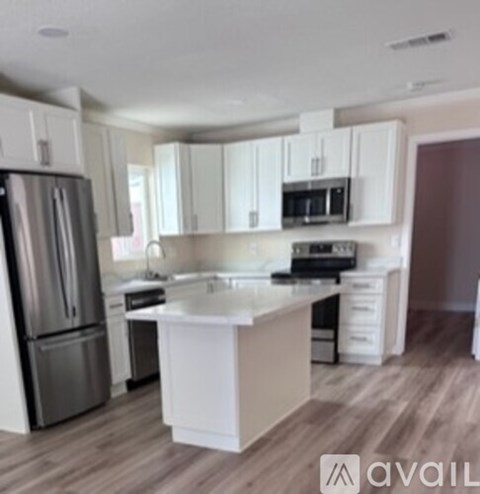 A kitchen with white cabinets and a stainless steel refrigerator.