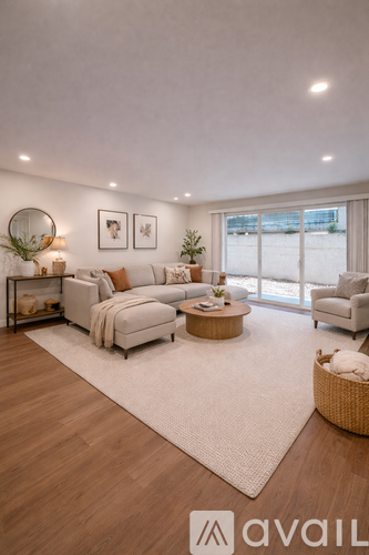 A modern living room with a white sofa set, a wooden coffee table, and a large window.