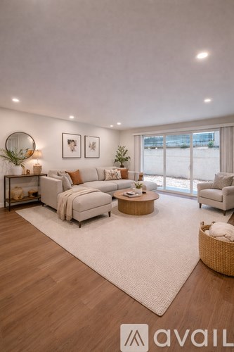 A modern living room with a white sofa set, a wooden coffee table, and a large window.