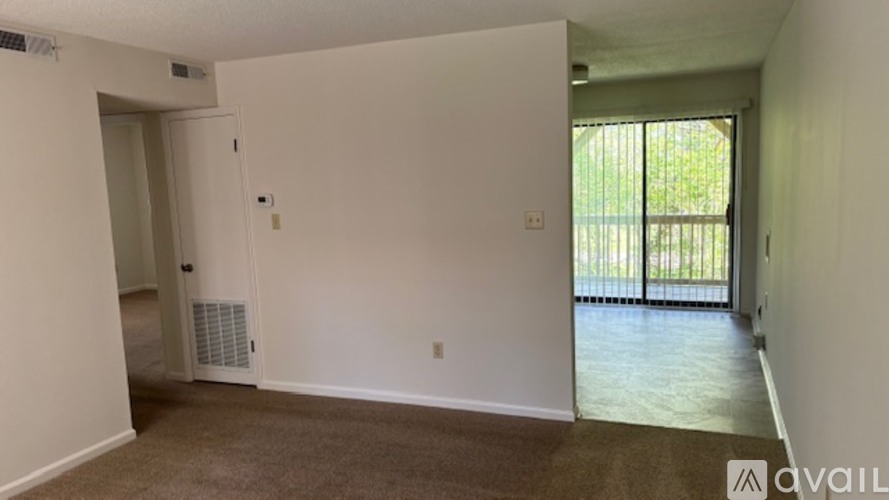 A room with a carpeted floor and a sliding glass door leading to a balcony.