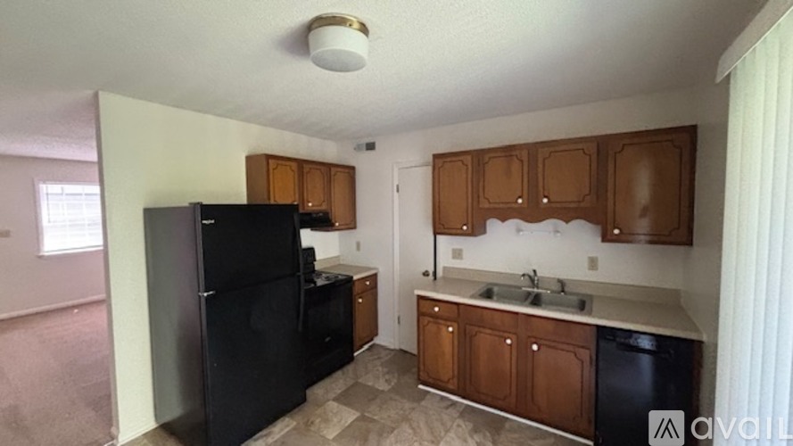 A kitchen with black appliances and wooden cabinets.