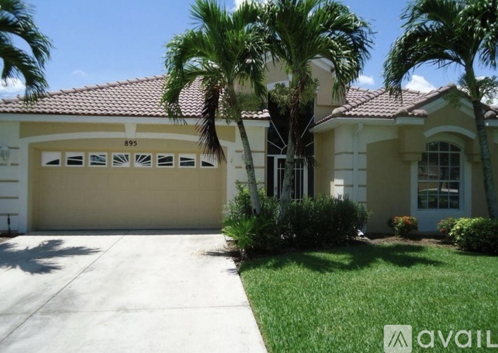 A house with a garage and palm trees in front.