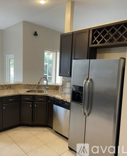 A kitchen with a stainless steel refrigerator and black cabinets.