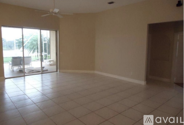 A spacious room with a fan and sliding glass doors leading to a balcony.