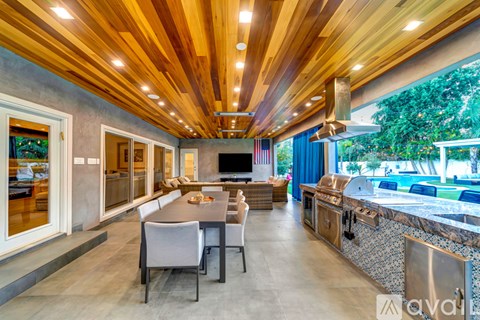 A modern kitchen with a wooden ceiling and a dining table with chairs.
