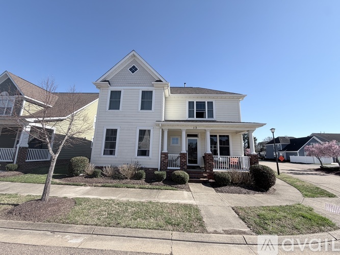 A white two-story house with a front porch and a small tree.