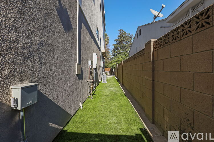 A narrow alley with grass on the ground and buildings on either side.