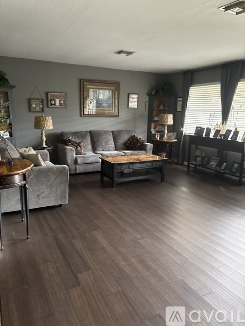 A living room with a grey couch, a coffee table, and a lamp.