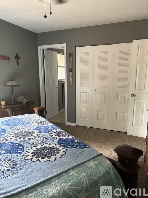 A bedroom with a bed covered in a blue floral comforter.