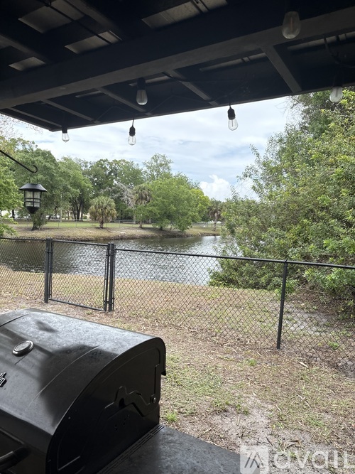 A black grill is in the foreground of a view of a lake and trees.