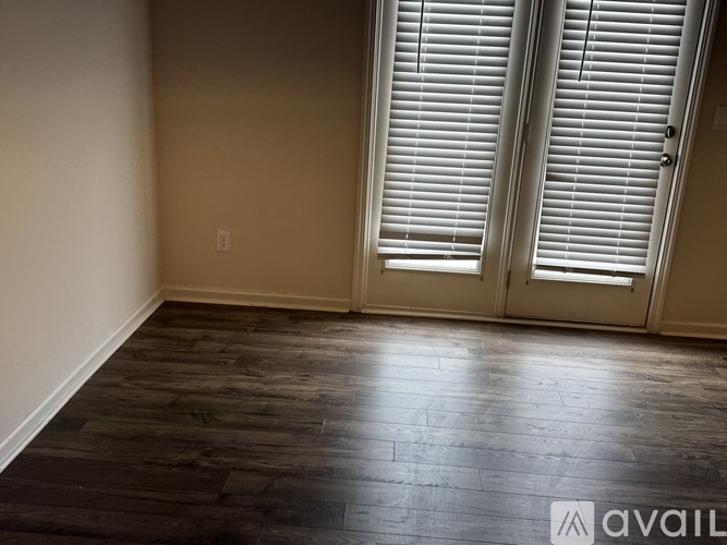 A room with wooden floors and a pair of white shutters on the window.