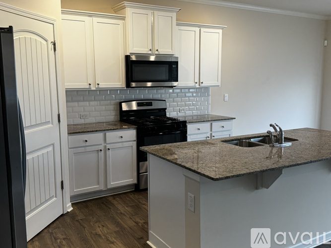 A kitchen with white cabinets and a granite countertop.