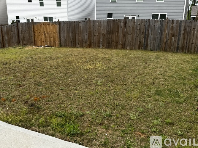 A backyard with a wooden fence and a grassy area.