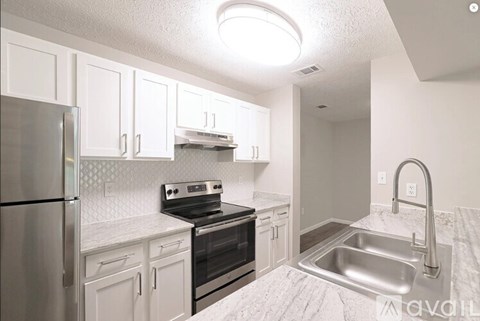 A kitchen with white cabinets and a stainless steel refrigerator.