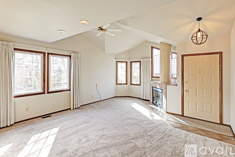 A spacious living room with a ceiling fan and large windows.