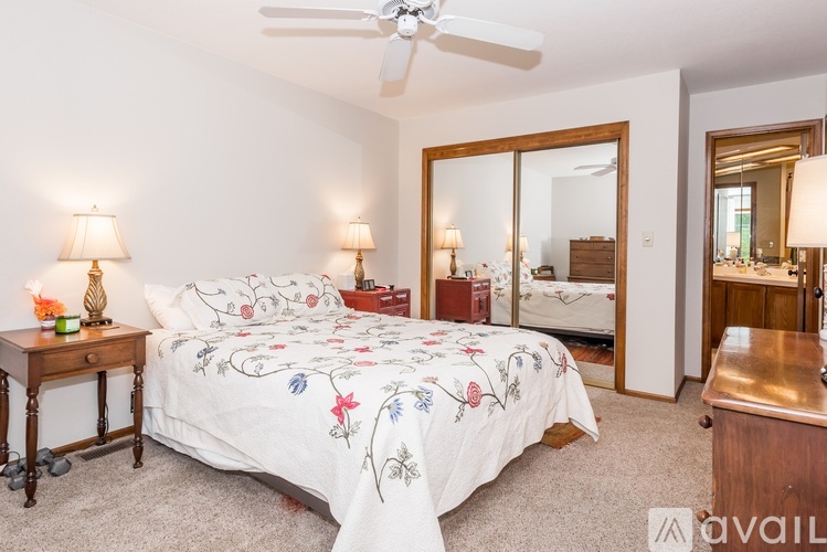 A bedroom with a floral bedspread and a ceiling fan.