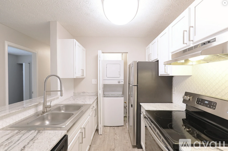 A kitchen with a stove, sink, and refrigerator.