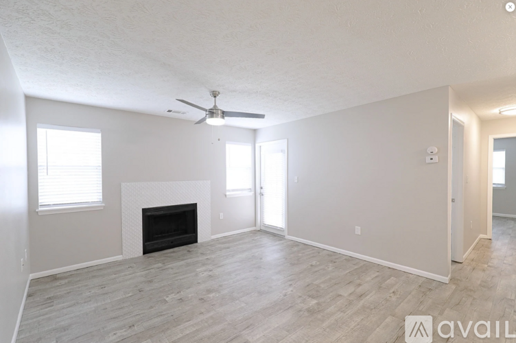A spacious living room with a fireplace and a ceiling fan.