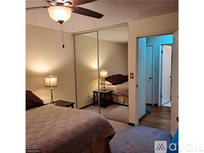 A bedroom with a bed, a nightstand with a lamp, and a mirror.