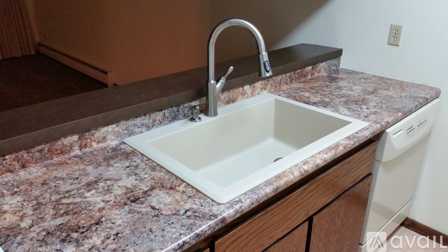A kitchen sink with a granite countertop and a white faucet.