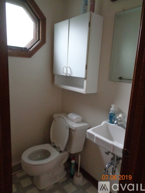 A bathroom with a toilet, sink, and cabinets.