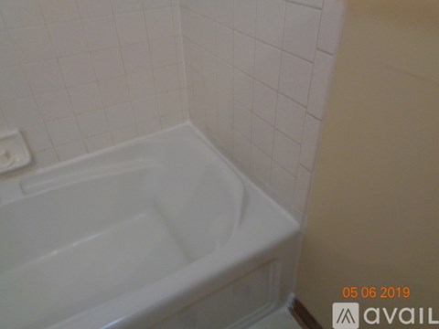 A white bathtub in a bathroom with white tiles.