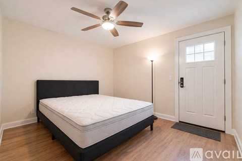 A bedroom with a bed, a ceiling fan, and a door.