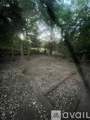 A gravel area surrounded by trees with a wooden fence.