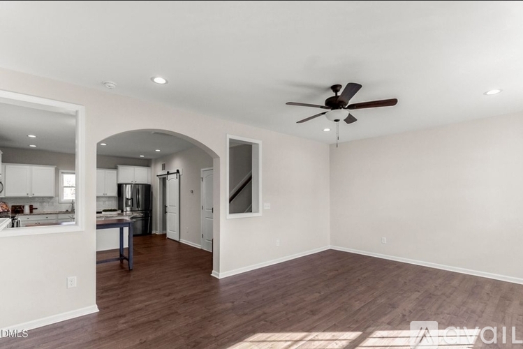 A spacious room with a ceiling fan and wooden flooring.