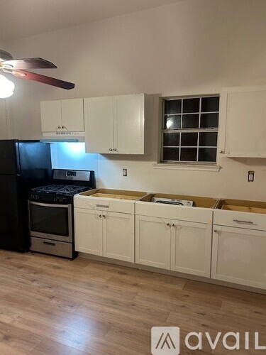 A kitchen with white cabinets and a black fridge.