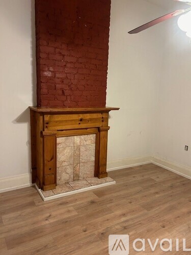 A room with a wooden fireplace and a red brick wall.