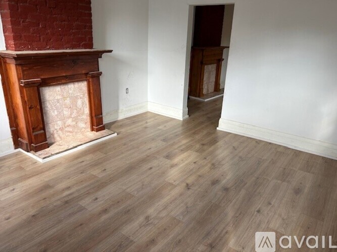 A room with a fireplace and wood flooring.