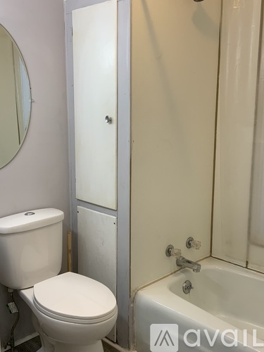 A white toilet sits next to a white bathtub in a bathroom.