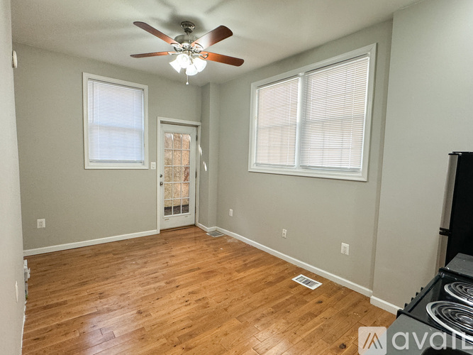 A room with a ceiling fan and two windows.
