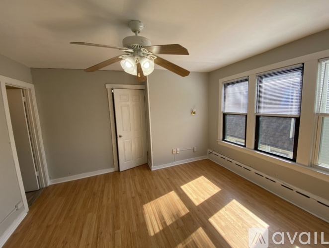A room with a ceiling fan and wooden flooring.