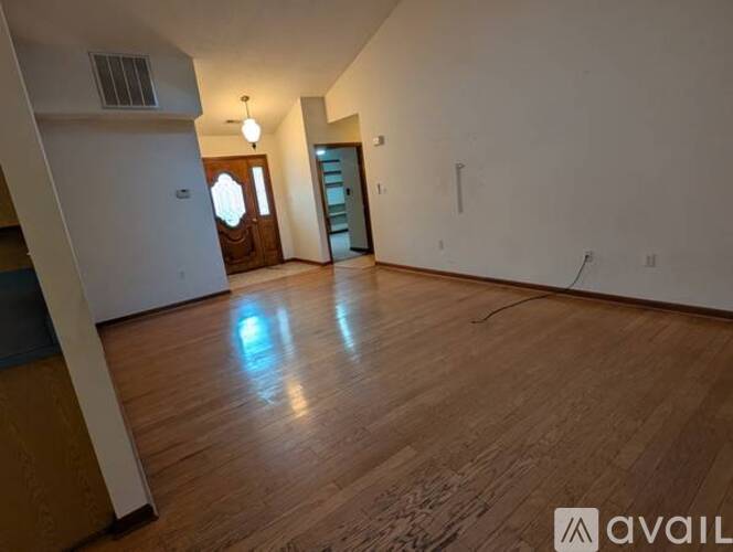 A spacious room with wooden flooring and a doorway leading to another room.
