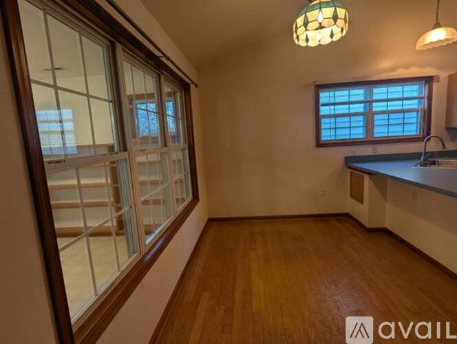 A kitchen with wooden floors and a window with blinds.