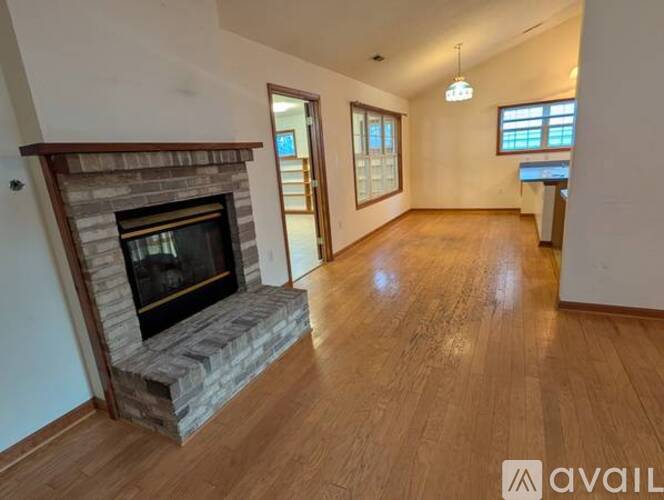 A spacious living room with a stone fireplace and wooden flooring.