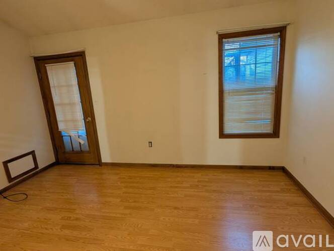 A room with wooden flooring and a window with blinds.