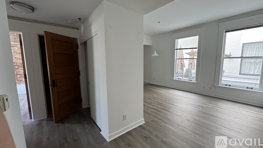 A room with a wooden door and a window with white curtains.