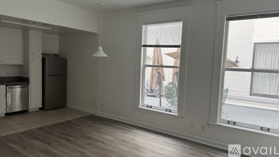 A kitchen area with a refrigerator, a dishwasher, and a window overlooking a balcony.