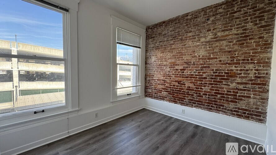 A room with a brick wall and wooden flooring is available for rent.
