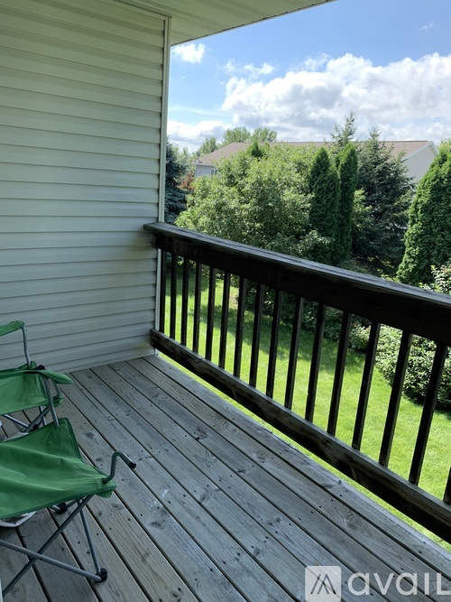 A balcony with a green chair and a view of the sky and trees.