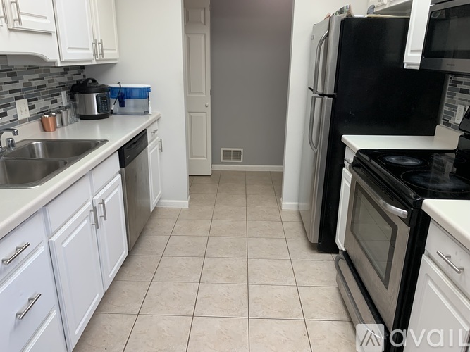 A kitchen with white cabinets and black appliances.